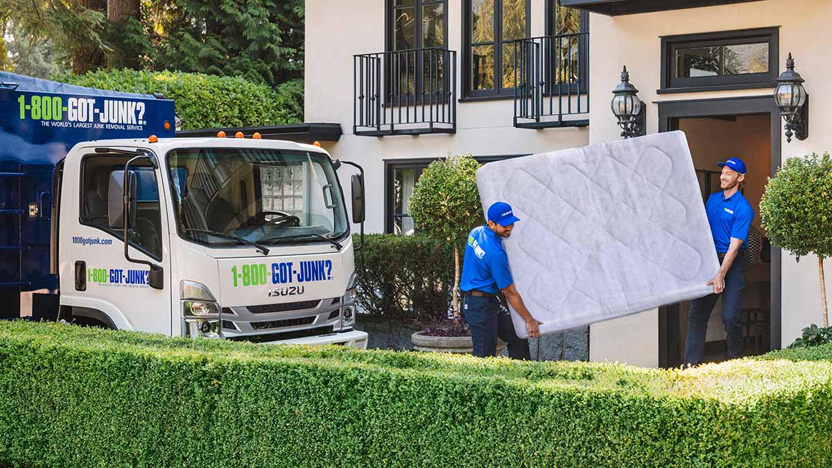 Top Items of 2023 Two 1-800-GOT-JUNK? team mebers carrying a large mattress out of a house.