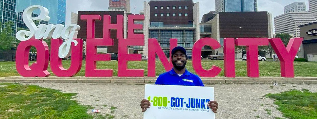 Sing Queen City 1-800-GOT-JUNK? Cincinnati 1-800-GOT-JUNK? Cincinnati team member standing at the Sing the Queen City sign in Freedom Park