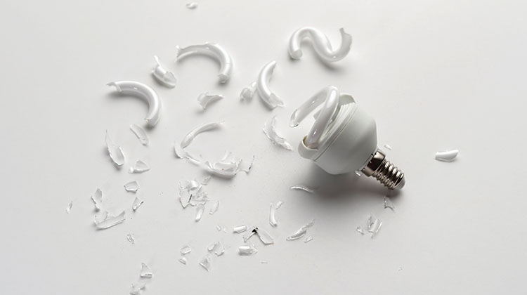 CFL bulb broke A broken CFL bulb with glass shards spread across white tabletop