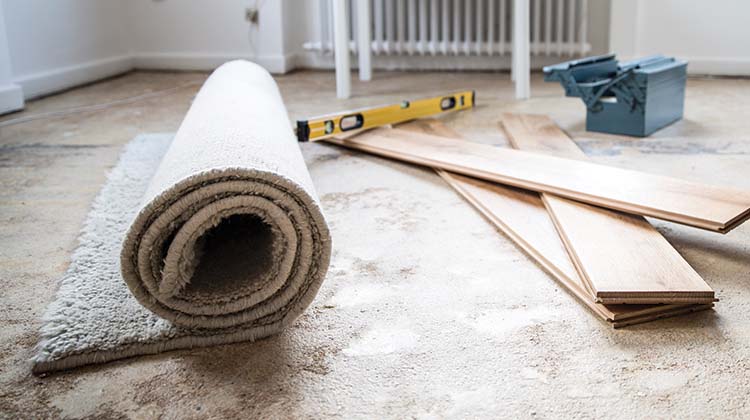 How to dispose of old carpet Rolled up carpet ready for disposal beside new flooring a level and a tool box